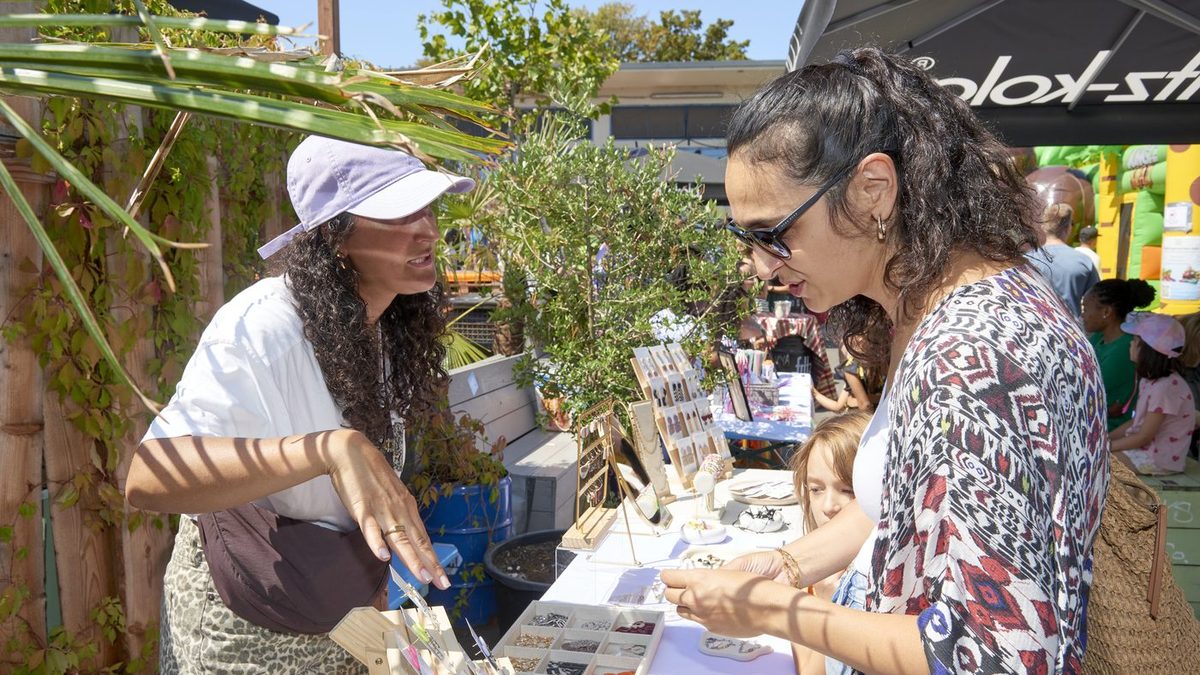 Stand mit Schmuck auf dem Auszeit! Markt, zwei Besucherinnen im Gespraech